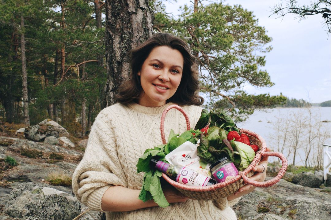 Kia Arpia rannalla kädessään korillinen ruoka-aineksia